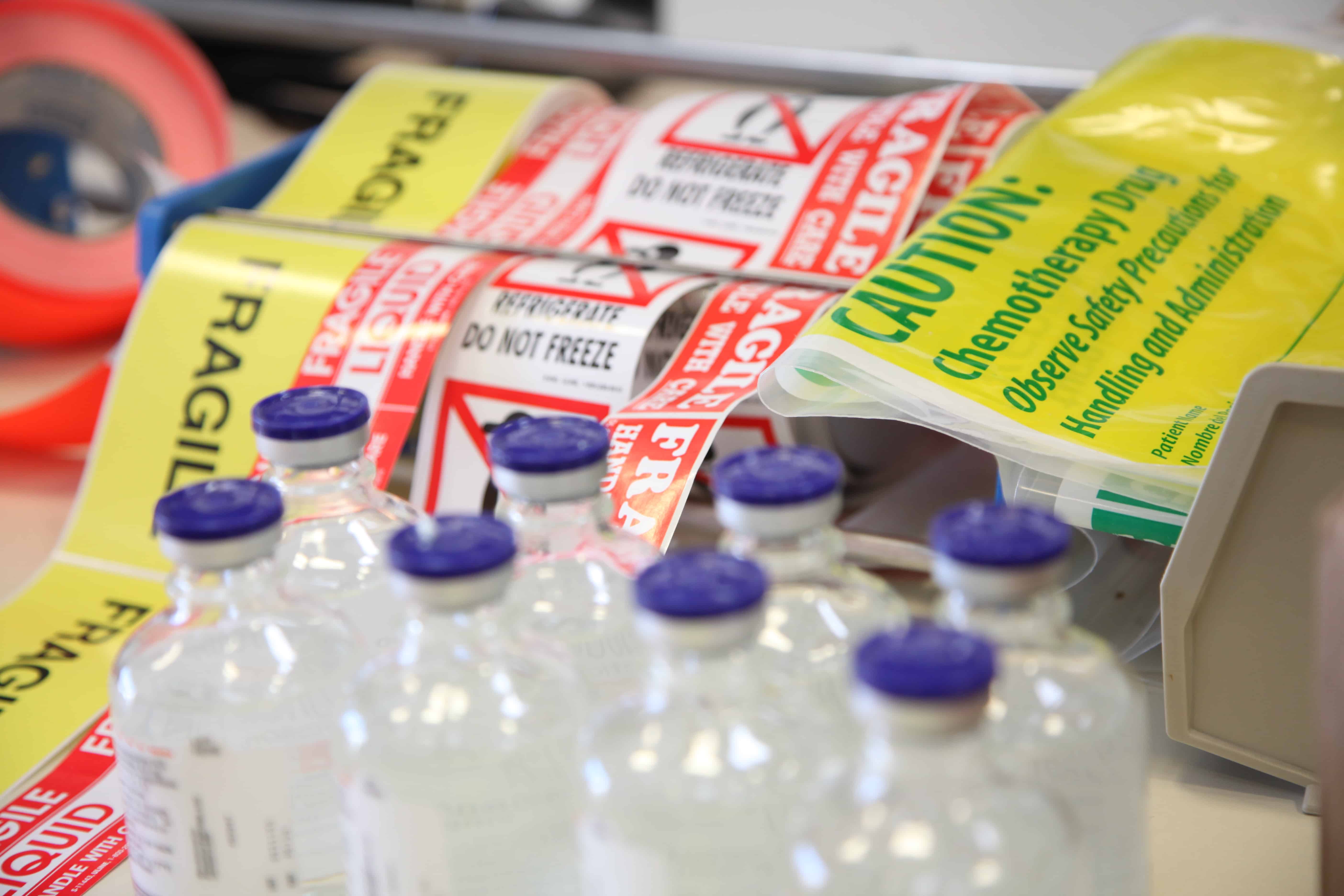 Labels and vials staged for compliant outbound packaging and traceability.